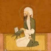 Portrait of a man with a beard seated on a rug.