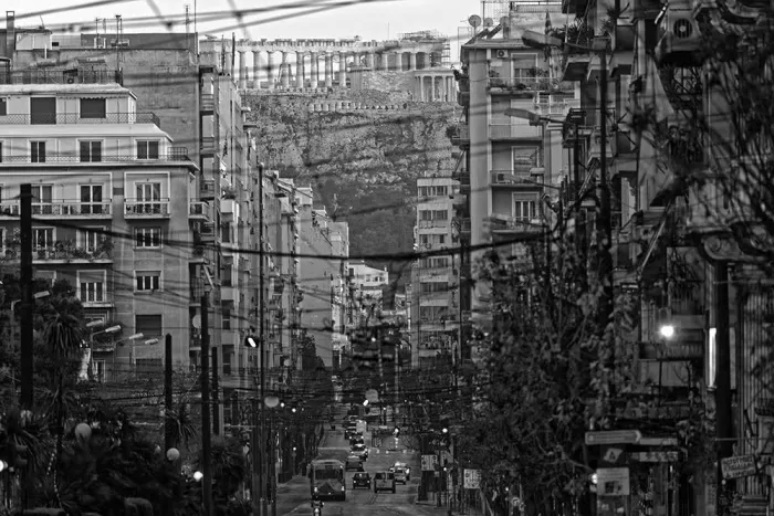 A monochrome cityscape with tall buildings and busy streets