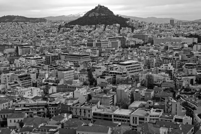 black and white image of a cityscape with a mountain in the distance