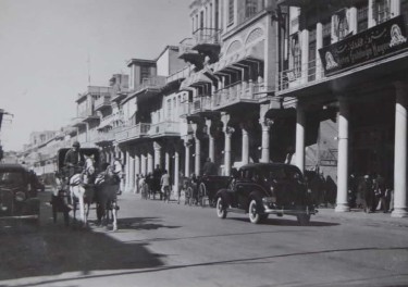 Historic image of a street featuring horse-drawn carriages