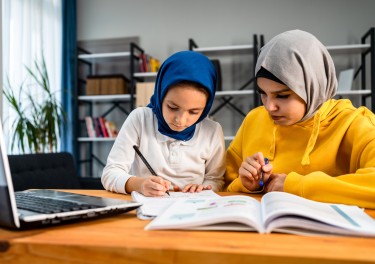 Muslim girl helping her sister with homework