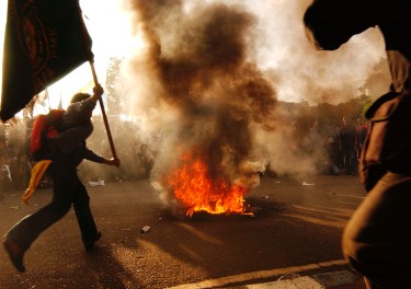 Indonesian students wave flags as tires burn during the fifth day of a demonstration rally in front of Presidential Palace January 10, 2002 in Jakarta, Indonesia.