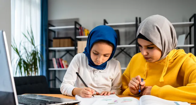 Muslim girl helping her sister with homework